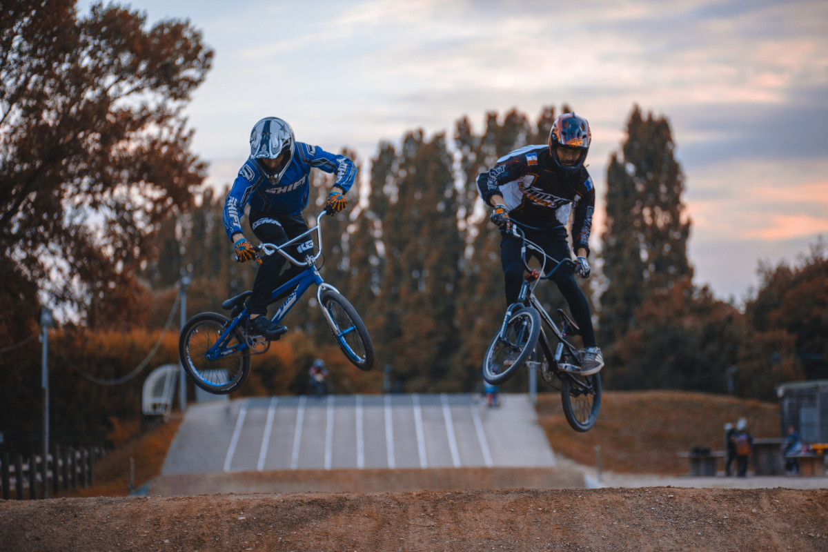 BMX to sport olimpijski - zdjęcie przedstawia dwóch zawodników bmx skaczących na torze bmx.
